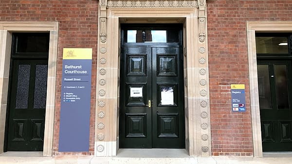 The closed front entrance of a courthouse, its doors set beneath a stone portico