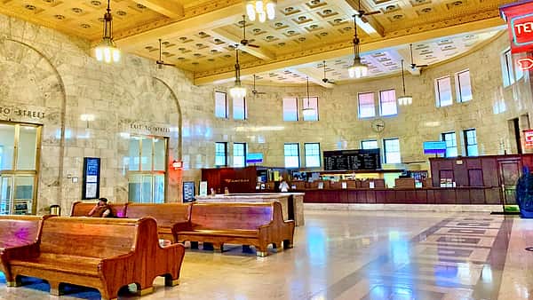 The waiting hall of a railway station with rows of empty wooden benches