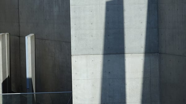 A plain concrete wall in daylight, its surface marked by age and fine cracks