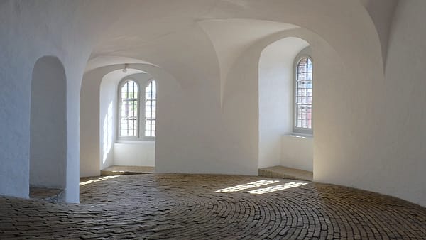 A wide spiral ramp rising through the interior of an old brick tower