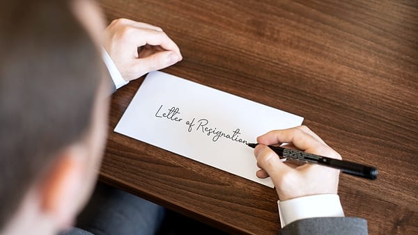 A handwritten letter lying on a desk beside a pen, its lines of script clearly visible