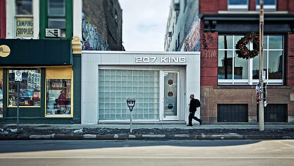 A shuttered shopfront on a city street with a passer-by walking in front of it
