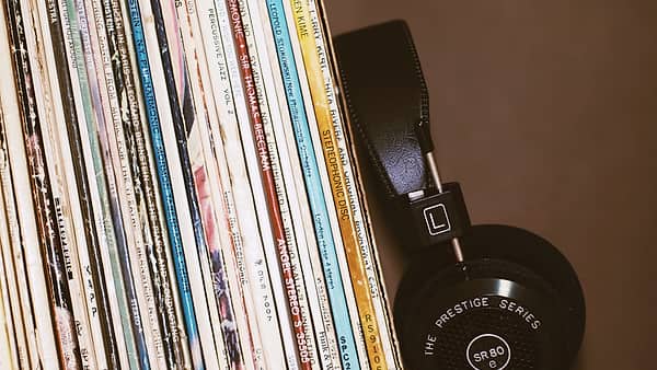 A pair of headphones resting against a row of record sleeves standing on a shelf