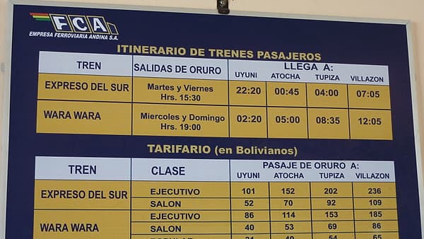 A printed departure timetable displayed on the wall of a railway station