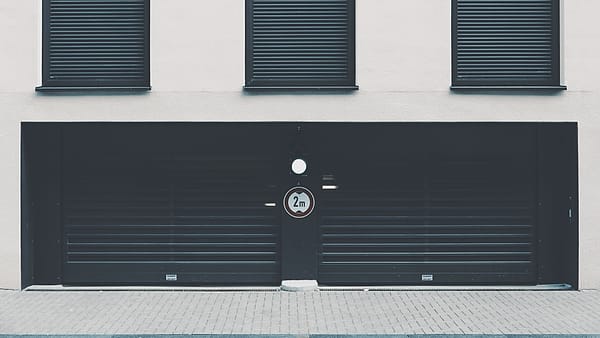 A metal shutter pulled fully down over an entrance beside a plain wall