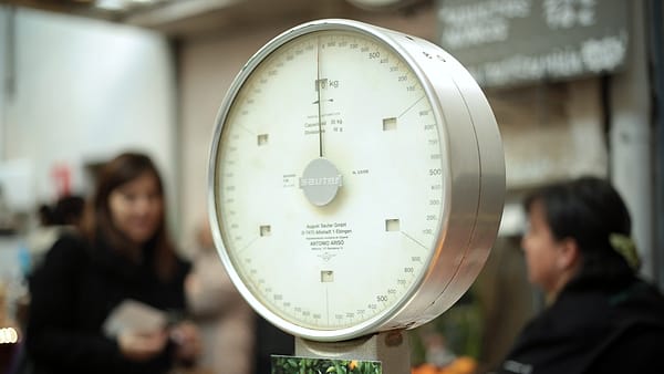 A set of old shop scales standing on a counter with its pan and dial visible