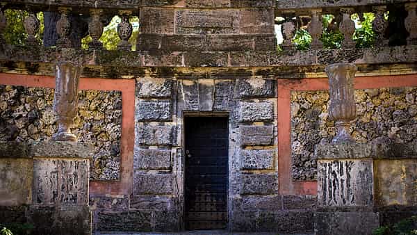 A weathered wooden door held shut by a lock and set into a plain stone doorway