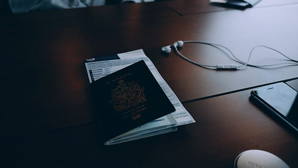 Travel documents and loose papers spread across a desk beside a pen
