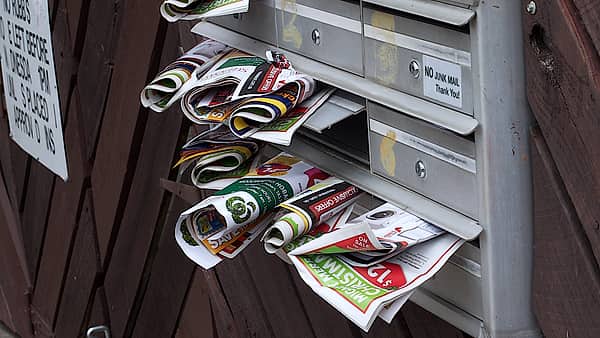 A domestic letter box crammed with unopened mail spilling out of the opening