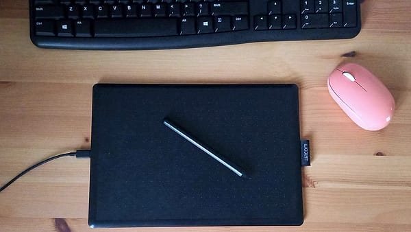 A tablet lying on a minimal desk beside a stylus and a closed notebook
