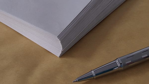 A silver pen lying beside several envelopes arranged across an office desk