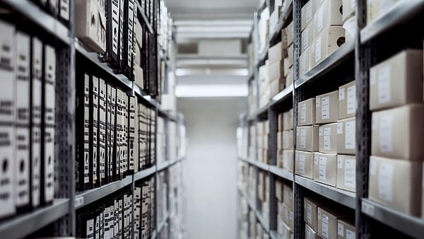 Rows of labeled archive boxes stacked on metal shelving in a storage room