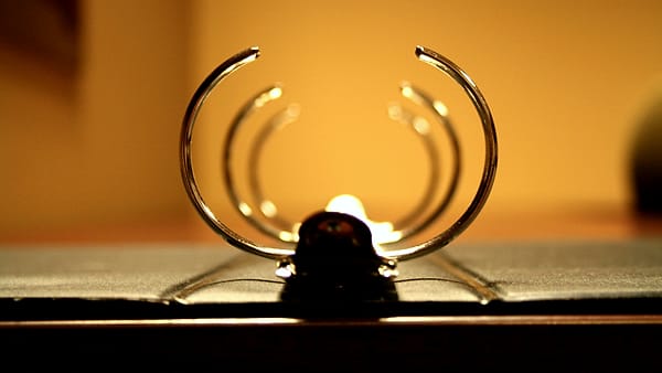 The metal rings of an open ring binder photographed close up against a dark ground
