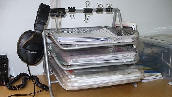Three stacked office trays holding loose paperwork on a working desk