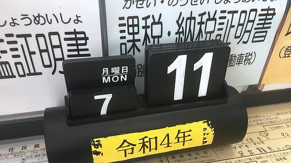 A small desk calendar standing open on a wooden surface with one month of dates showing