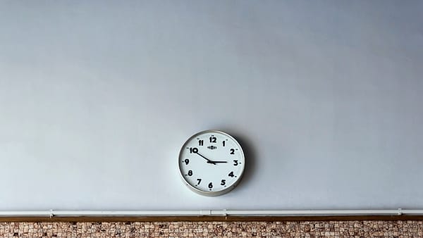 A plain round analog wall clock photographed straight on against a light-colored wall