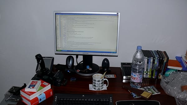 A cluttered working desk covered with papers, books and loose stationery