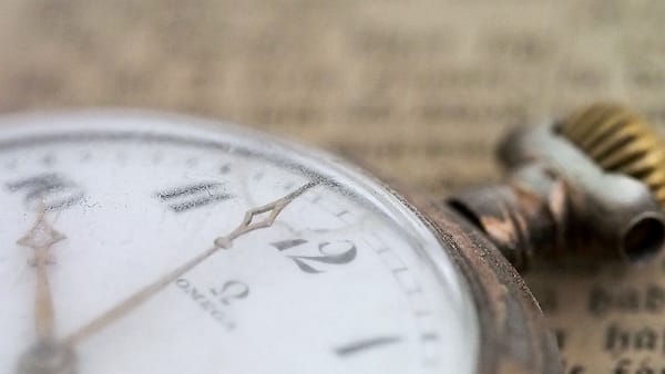 The face of an old pocket watch photographed in close-up, its numerals worn