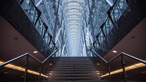 A long hallway lined with closed doors receding toward a lit far end