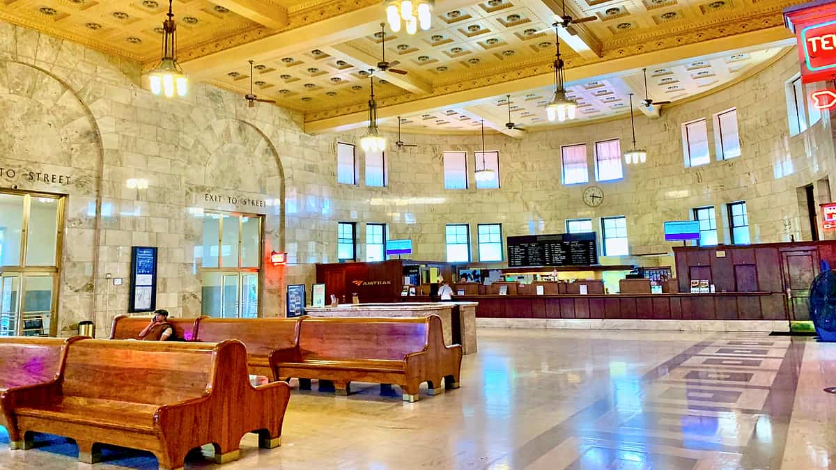 The waiting hall of a railway station with rows of empty wooden benches