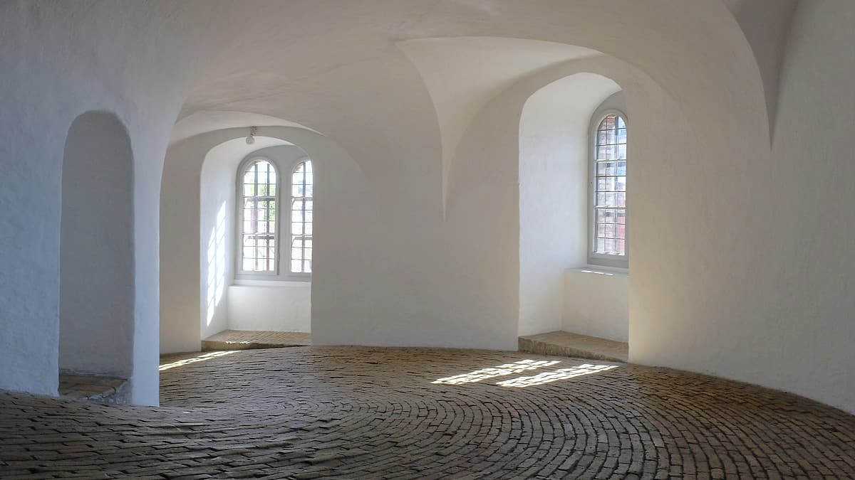 A wide spiral ramp rising through the interior of an old brick tower