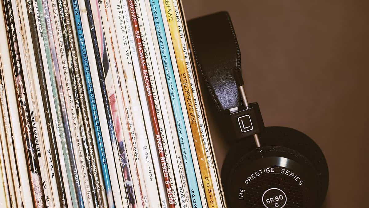 A pair of headphones resting against a row of record sleeves standing on a shelf