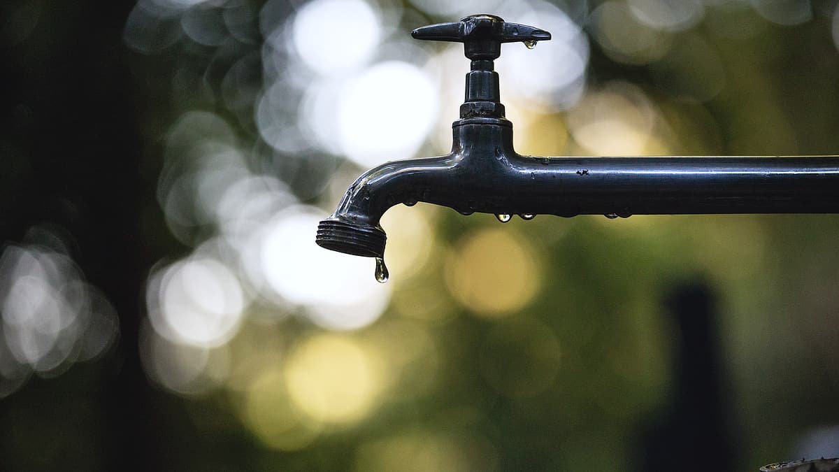 Water running steadily from a metal tap into a basin, caught in mid-flow