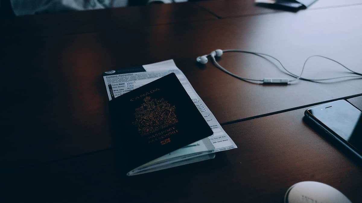 Travel documents and loose papers spread across a desk beside a pen