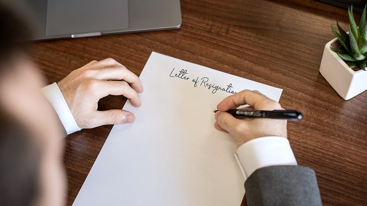Somebody writing a short letter by hand on a sheet of paper at a table