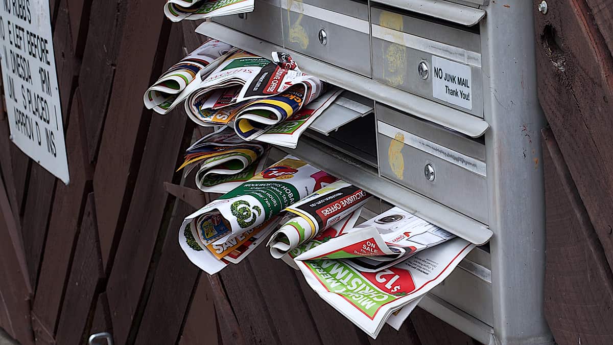 A domestic letter box crammed with unopened mail spilling out of the opening