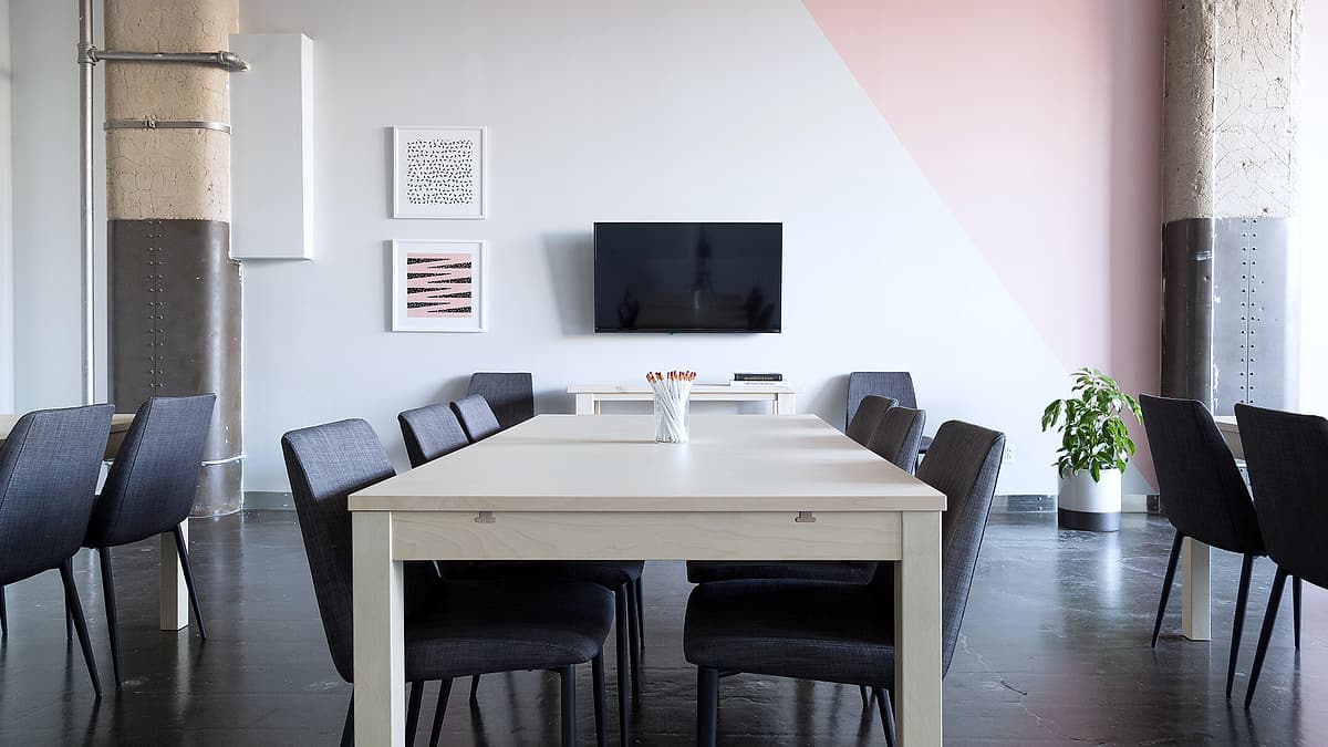 An empty meeting room with a bare table and chairs arranged neatly around it