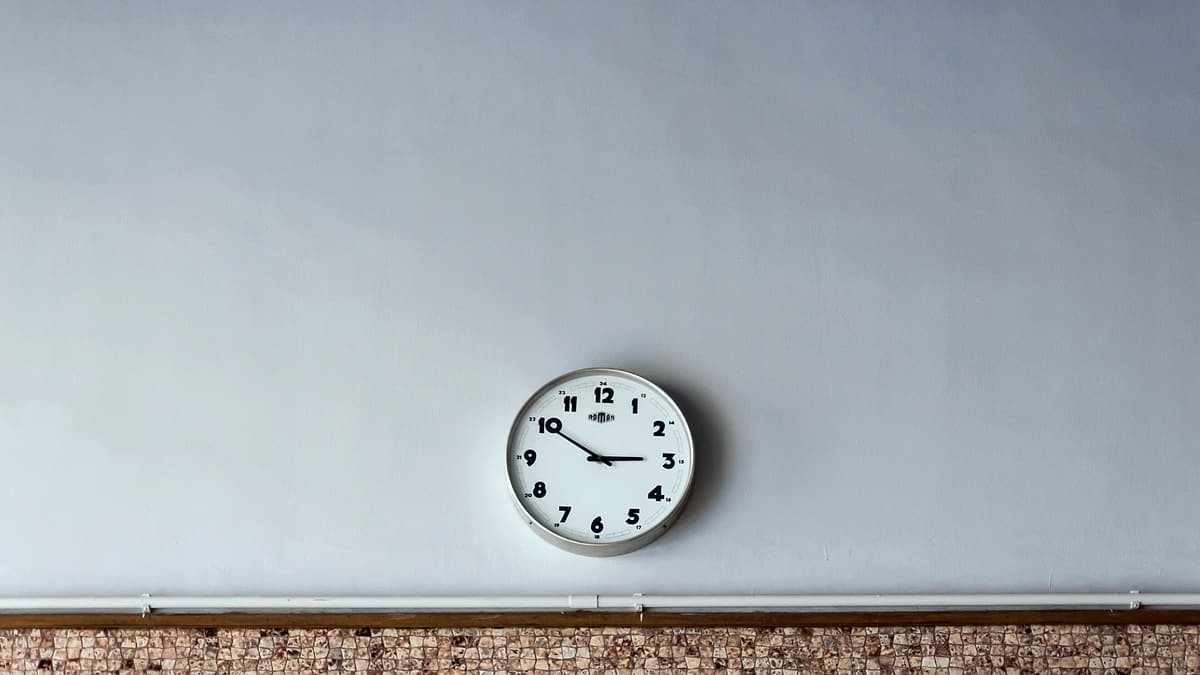 A plain round analog wall clock photographed straight on against a light-colored wall