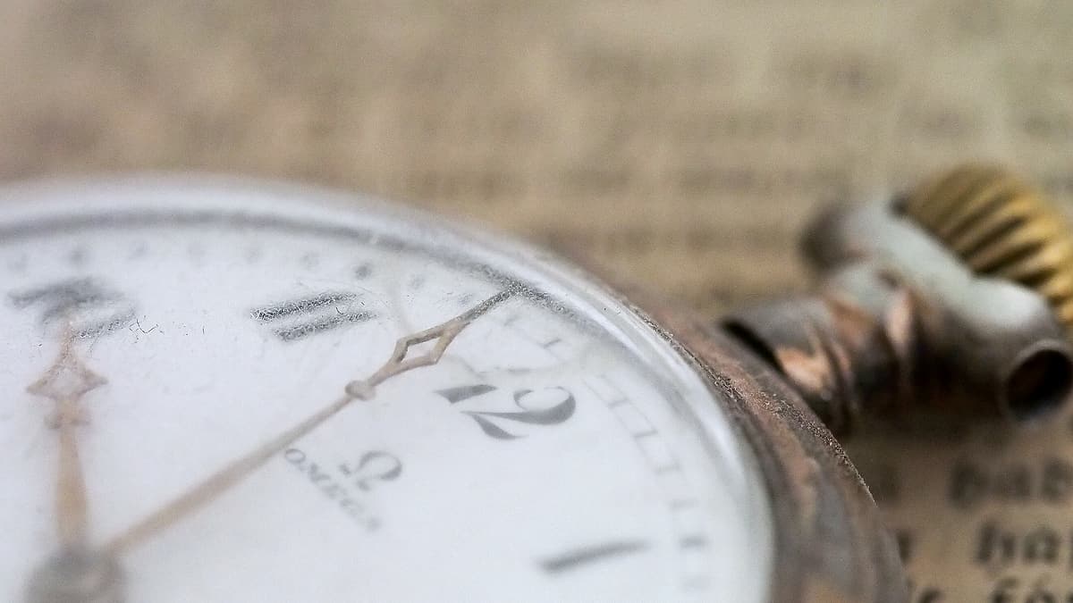 The face of an old pocket watch photographed in close-up, its numerals worn